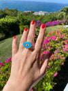 light blue evil eye glass ring on hand 